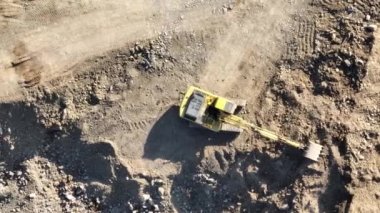 Endüstriyel maden kazıcıları inşaat alanındaki toprağı kazıyor ve kamyonları yüklüyor. Hava aracı üst görüntüsü. Merhaba kaliteli 4K video.