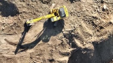 Endüstriyel maden kazıcıları inşaat alanındaki toprağı kazıyor ve kamyonları yüklüyor. Hava aracı üst görüntüsü. Merhaba kaliteli 4K video.