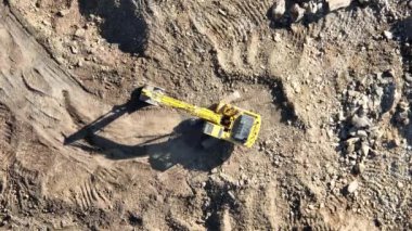 Endüstriyel maden kazıcıları inşaat alanındaki toprağı kazıyor ve kamyonları yüklüyor. Hava aracı üst görüntüsü. Merhaba kaliteli 4K video.