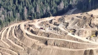 Endüstriyel maden kazıcıları inşaat alanındaki toprağı kazıyor ve kamyonları yüklüyor. Hava aracı üst görüntüsü. Merhaba kaliteli 4K video.