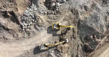Endüstriyel maden kazıcıları inşaat alanındaki toprağı kazıyor ve kamyonları yüklüyor. Hava aracı üst görüntüsü. Merhaba kaliteli 4K video.