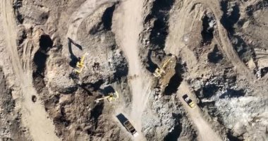Endüstriyel maden kazıcıları inşaat alanındaki toprağı kazıyor ve kamyonları yüklüyor. Hava aracı üst görüntüsü. Merhaba kaliteli 4K video.