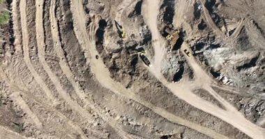 Endüstriyel maden kazıcıları inşaat alanındaki toprağı kazıyor ve kamyonları yüklüyor. Hava aracı üst görüntüsü. Merhaba kaliteli 4K video.