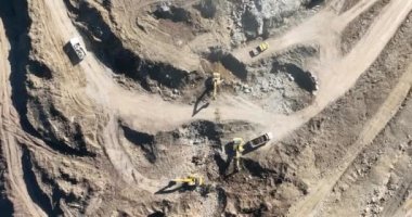 Endüstriyel maden kazıcıları inşaat alanındaki toprağı kazıyor ve kamyonları yüklüyor. Hava aracı üst görüntüsü. Merhaba kaliteli 4K video.