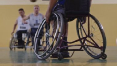 Tekerlekli sandalyede oturan ve spor salonunda basketbol oynayan engelli bir sporcunun yakın çekimi. Seçici odaklanma. Yüksek kalite 4K video. 