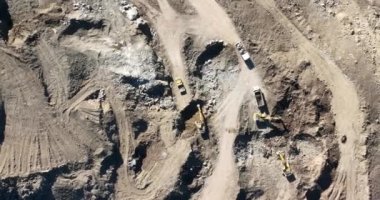 Endüstriyel maden kazıcıları inşaat alanındaki toprağı kazıyor ve kamyonları yüklüyor. Hava aracı üst görüntüsü. Merhaba kaliteli 4K video.