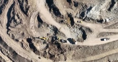 Endüstriyel maden kazıcıları inşaat alanındaki toprağı kazıyor ve kamyonları yüklüyor. Hava aracı üst görüntüsü. Merhaba kaliteli 4K video.