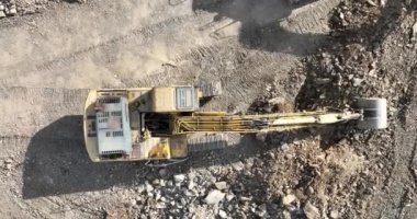 Endüstriyel maden kazıcıları inşaat alanındaki toprağı kazıyor ve kamyonları yüklüyor. Hava aracı üst görüntüsü. Merhaba kaliteli 4K video.