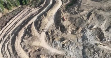 Endüstriyel maden kazıcıları inşaat alanındaki toprağı kazıyor ve kamyonları yüklüyor. Hava aracı üst görüntüsü. Merhaba kaliteli 4K video.