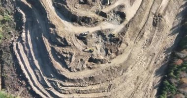 Endüstriyel maden kazıcıları inşaat alanındaki toprağı kazıyor ve kamyonları yüklüyor. Hava aracı üst görüntüsü. Merhaba kaliteli 4K video.