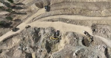 Endüstriyel maden kazıcıları inşaat alanındaki toprağı kazıyor ve kamyonları yüklüyor. Hava aracı üst görüntüsü. Merhaba kaliteli 4K video.