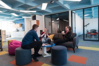 Çok ırklı bir girişim ekibi modern, açık alan çalışma ofisinde toplanıyor. Beyin fırtınası, dizüstü bilgisayarda çalışmak. Hareket bulanıklığı içinde dolaşan bir grup iş arkadaşı