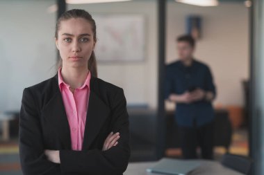 Gencecik gülümseyen iş kadınının portresi. Yaratıcı açık mekan ortak çalışma ofisinde. Başarı sahibi iş kadını, kopyalama alanı ile ofiste duruyor. Arka planda çalışan iş arkadaşları