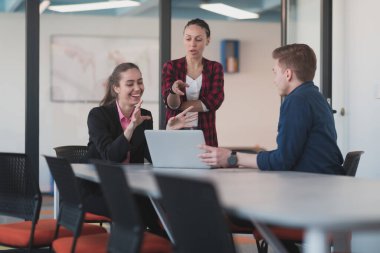 Pembe gömlekli başarılı bir bayan lider kararlı bir gülümsemeyle modern cam bir ofiste oturuyor. İş anlayışı ve modern online işlerdeki gençlerin başarısı. 