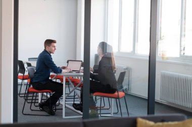 Pembe gömlekli başarılı bir bayan lider kararlı bir gülümsemeyle modern cam bir ofiste oturuyor. İş anlayışı ve modern online işlerdeki gençlerin başarısı. 