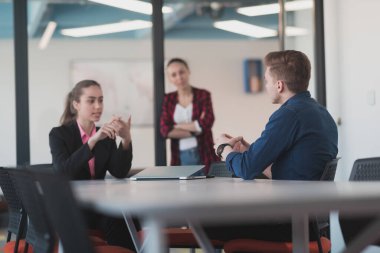 Pembe gömlekli başarılı bir bayan lider kararlı bir gülümsemeyle modern cam bir ofiste oturuyor. İş anlayışı ve modern online işlerdeki gençlerin başarısı. 