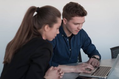 Pembe gömlekli başarılı bir bayan lider kararlı bir gülümsemeyle modern cam bir ofiste oturuyor. İş anlayışı ve modern online işlerdeki gençlerin başarısı. 