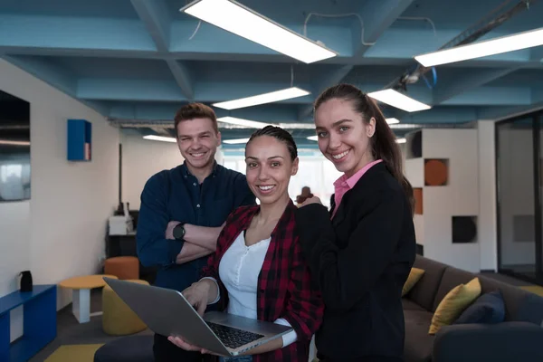 現代のオフィスで若い熱狂的な若いビジネスの人々のグループ 彼女の手にノートパソコンを持つビジネスの女性は 両腕を組んでいる背景の同僚で — ストック写真