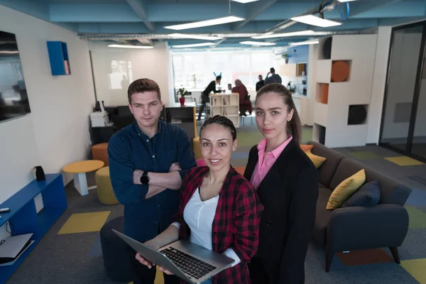 一群热情洋溢的年轻人在一个现代化的办公室里 一位手里拿着笔记本电脑的女商人 背景中的同事们手挽手 — 图库照片