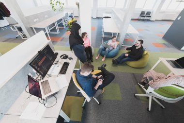 Ofiste yapılan beyin fırtınası sırasında çok kültürlü genç iş adamlarının işbirliği sürecinin en üst görüntüsü. Resmi olarak giyinmiş çeşitli gençler iş birliği yapıyor.