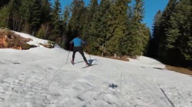 Bir atlet, güzel bir sabah karlı bir yolda çıplak ağaçların arasında kayak sporu yapar. Yüksek kalite 4K İHA görüntüleri