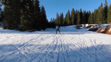 Bir atlet, güzel bir sabah karlı bir yolda çıplak ağaçların arasında kayak sporu yapar. Yüksek kalite 4K İHA görüntüleri