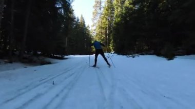 Bir atlet, güzel bir sabah karlı bir yolda çıplak ağaçların arasında kayak sporu yapar. Yüksek kalite 4K İHA görüntüleri