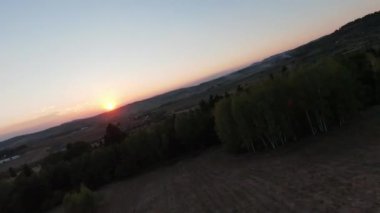 Arka planda güzel bir günbatımı olan güzel çam ağaçları ile tepenin üzerinden hızlı ve manevra yapılabilir bir uçuş. FPV insansız hava aracı ile çekildi. Yüksek kalite 4k görüntü