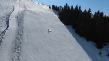 Karlı kışta dağ ve bulutlu bir günde yamaçta kayak yapan insanlar. FPV İHA Jahorina, Bosna-Hersek Olimpiyat Dağı. Yüksek kalite 4K görüntü