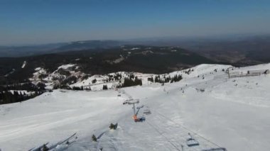 Karlı kışta dağ ve bulutlu bir günde yamaçta kayak yapan insanlar. FPV İHA Jahorina, Bosna-Hersek Olimpiyat Dağı. Yüksek kalite 4K görüntü