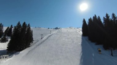 Karlı kışta dağ ve bulutlu bir günde yamaçta kayak yapan insanlar. FPV İHA Jahorina, Bosna-Hersek Olimpiyat Dağı. Yüksek kalite 4K görüntü