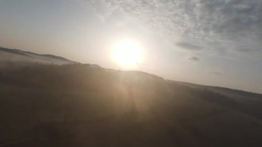 Arka planda güzel bir günbatımı olan orman ve ağaç tepeleriyle tepenin üzerinden hızlı ve manevra yapılabilir bir uçuş. FPV insansız hava aracı ile çekildi. Yüksek kalite 4k görüntü