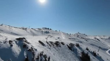 Karlı kışta dağ ve bulutlu bir günde yamaçta kayak yapan insanlar. FPV İHA Jahorina, Bosna-Hersek Olimpiyat Dağı. Yüksek kalite 4K görüntü