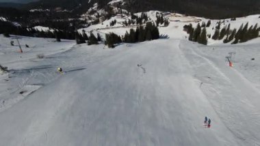 Karlı kışta dağ ve bulutlu bir günde yamaçta kayak yapan insanlar. FPV İHA Jahorina, Bosna-Hersek Olimpiyat Dağı. Yüksek kalite 4K görüntü