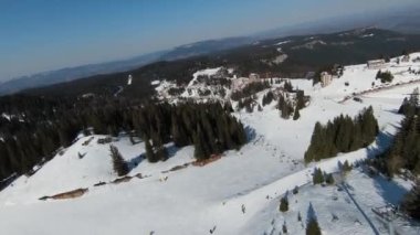 Karlı kışta dağ ve bulutlu bir günde yamaçta kayak yapan insanlar. FPV İHA Jahorina, Bosna-Hersek Olimpiyat Dağı. Yüksek kalite 4K görüntü