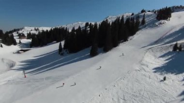 Karlı kışta dağ ve bulutlu bir günde yamaçta kayak yapan insanlar. FPV İHA Jahorina, Bosna-Hersek Olimpiyat Dağı. Yüksek kalite 4K görüntü