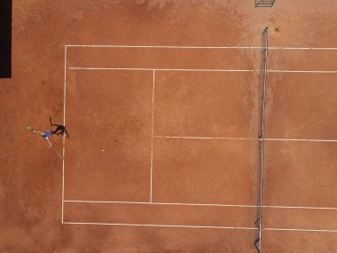 Kahverengi sahada oynayan genç bir bayan tenisçinin havadan görünüşü. Profesyonel tenisçi kız saha düz saha spor arka planında ters vuruş yapıyor. Yüksek kalite fotoğraf