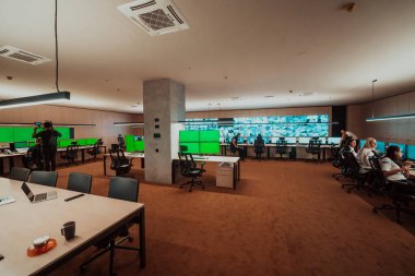 Professional videographer with gimball video slr recording video of Security data center operators while working in a CCTV monitoring room looking on multiple monitors Team working on the System Con