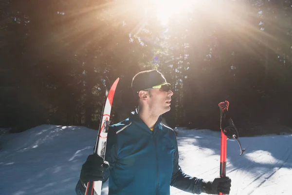 形象英俊的男性运动员 手拿越野滑雪板和护目镜 在雪地的森林里接受训练 健康的冬季生活方式概念 高质量的照片 — 图库照片