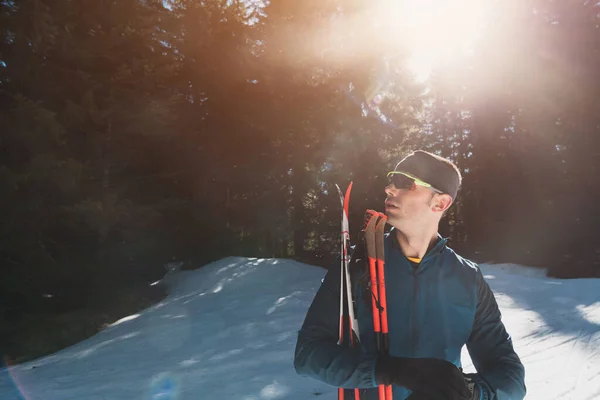 形象英俊的男性运动员 手拿越野滑雪板和护目镜 在雪地的森林里接受训练 健康的冬季生活方式概念 高质量的照片 — 图库照片