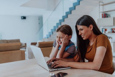 Anne ve kızı dizüstü bilgisayarda ailesi ve arkadaşlarıyla konuşuyorlardı. Büyük evin modern oturma odasında oturuyorlardı..