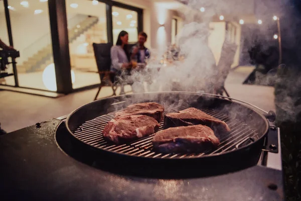 焼き肉の美味しい肉のクローズアップ写真 背景には 友人や家族が座って食事を待っています — ストック写真