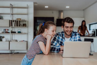 Baba ve kızı modern evde tatillerde aileleriyle birlikte dizüstü bilgisayarda konuşuyorlar. Modern bir ailenin hayatı..