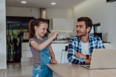 Baba ve kızı modern evde tatillerde aileleriyle birlikte dizüstü bilgisayarda konuşuyorlar. Modern bir ailenin hayatı..