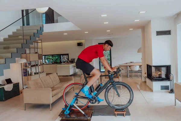 A man riding a triathlon bike on a machine simulation in a modern living room. Training during pandemic conditions
