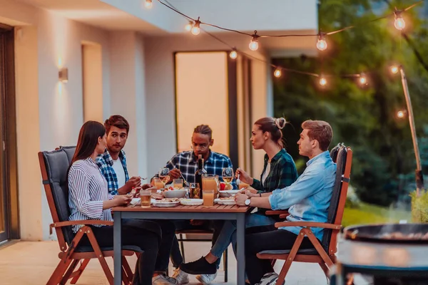 一群不同的年轻人 晚上在一座现代化的房子的阳台上吃饭 朋友和家人的乐趣 庆祝节日 举行烧烤婚礼 — 图库照片