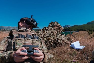 Bölgeyi gözlemlemek için bir asistanın yardımıyla keskin nişancı asker. Modern savaş taktiksel sanal gerçeklik gözlükleri hava insansız hava aracı askeri teknolojisini hedef alıyor.