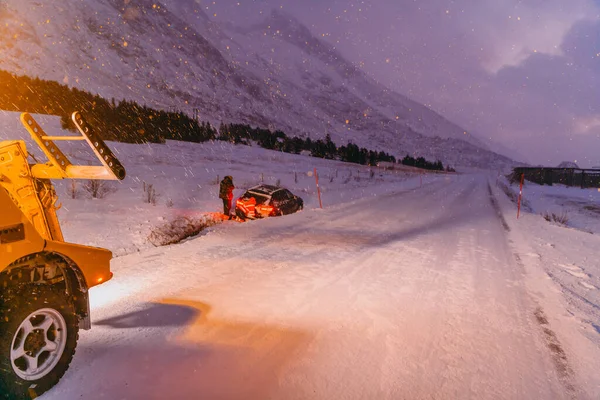 공사에서는 자동차를 밖으로 끌어내고 얼어붙은 스칸디나비아 도로에서 있었던 — 스톡 사진
