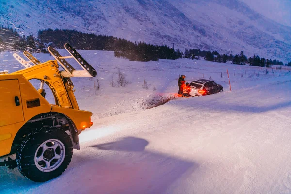 공사에서는 자동차를 밖으로 끌어내고 얼어붙은 스칸디나비아 도로에서 있었던 — 스톡 사진