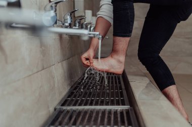 Bir müslüman abdest alıyor. Dua etmeden önce Müslümanların dini temizliği. Namazdan önce vücudu temizleme süreci. 